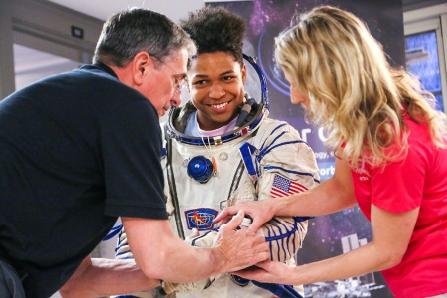 Astronaut Don Thomas and Higher Orbits CEO Michelle Lucas help a student in an EVA suit